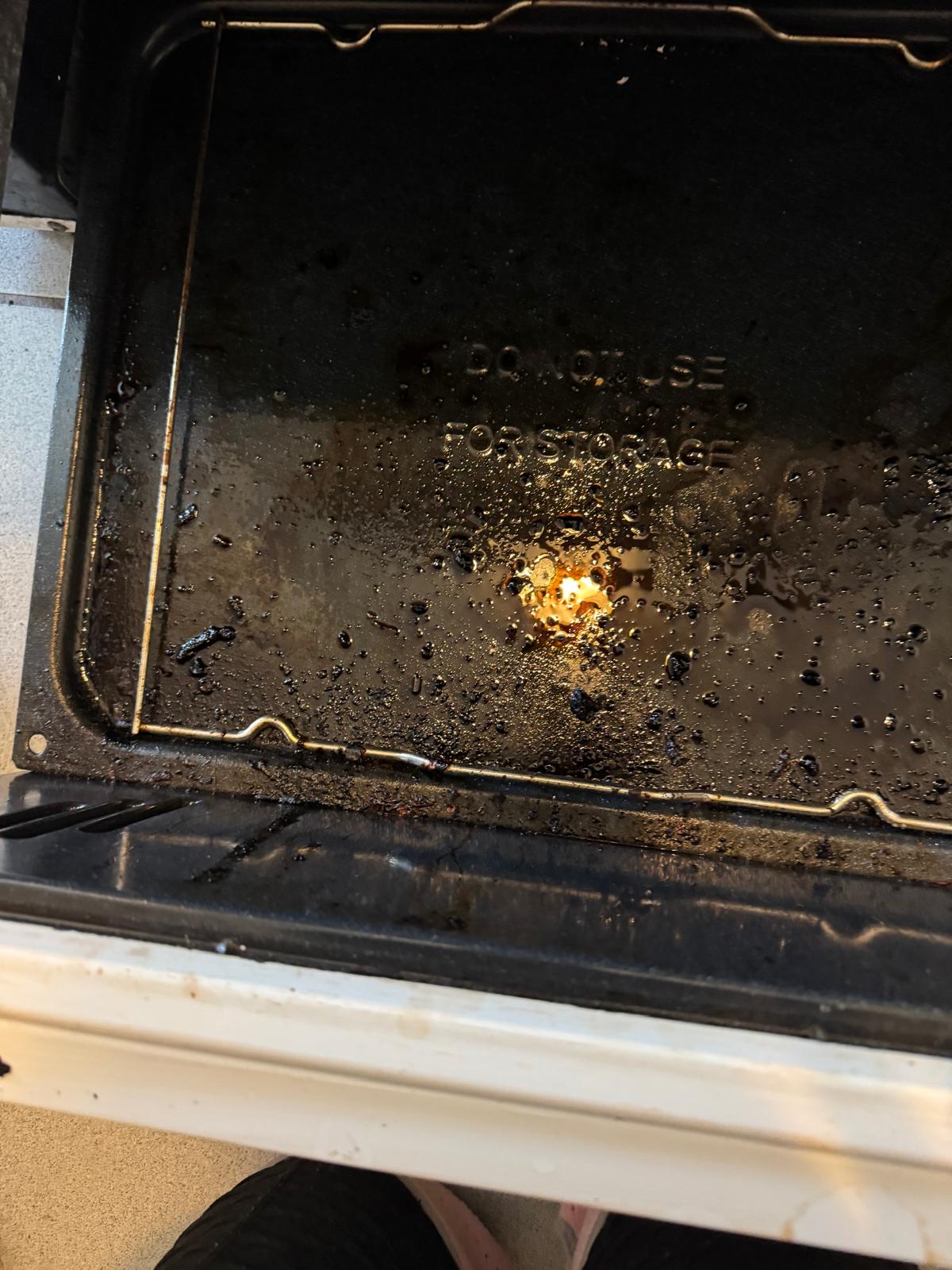 Oven door heavily covered in baked-on grease before deep cleaning