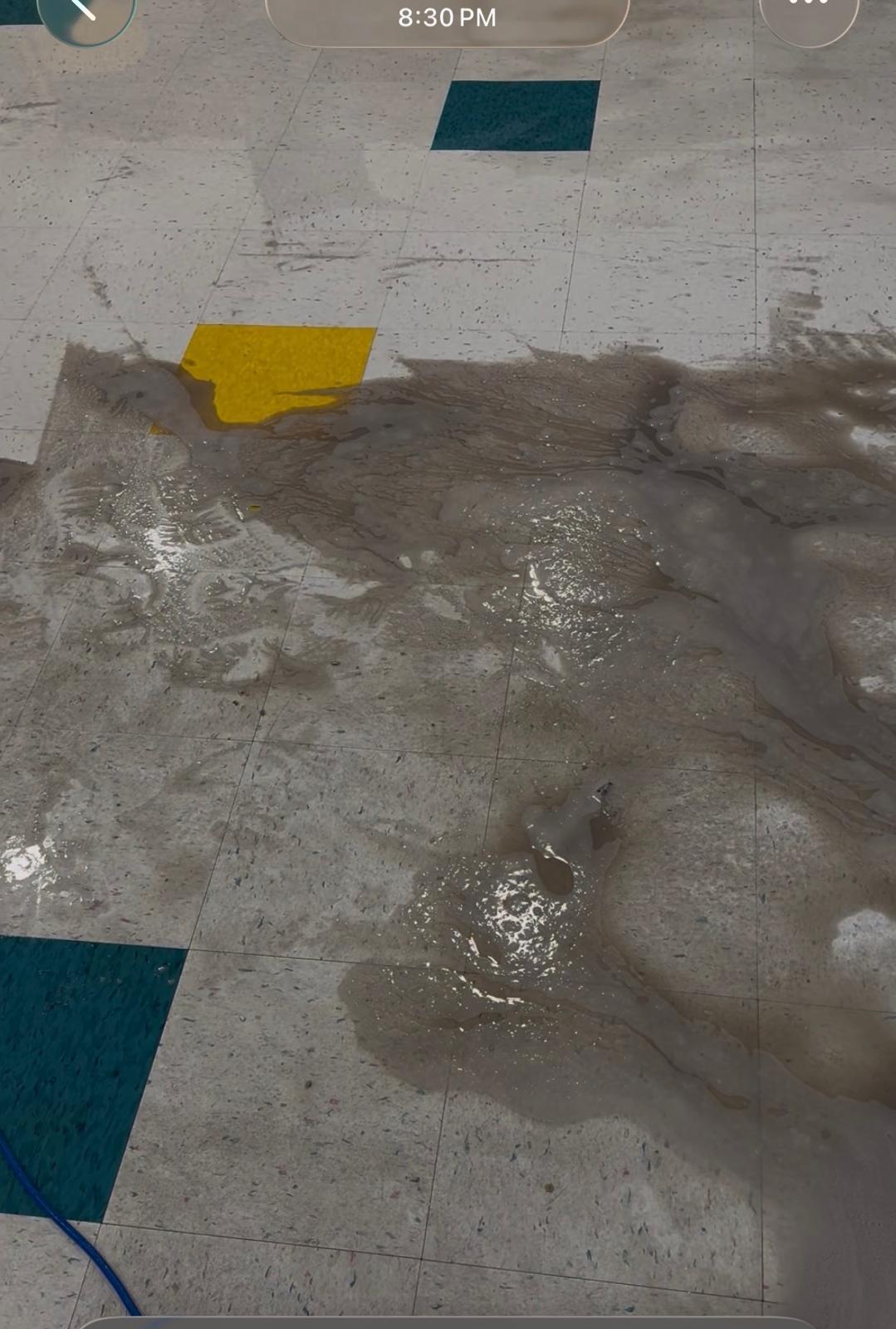 Commercial tile floor covered in dirty water and grime during cleaning