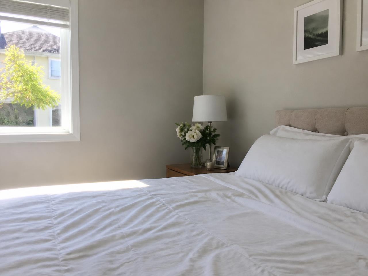 Neatly made bed with crisp white linens in a sunlit bedroom